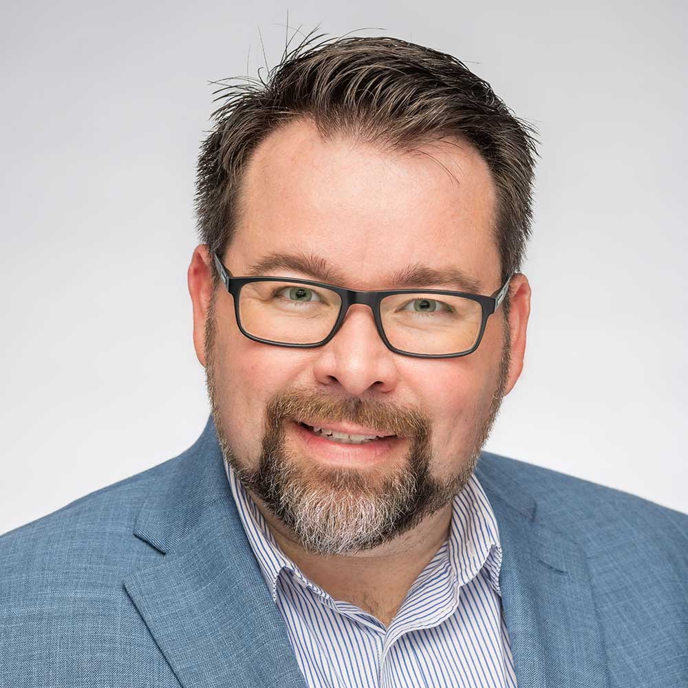 Man wearing glasses and blue blazer smiling