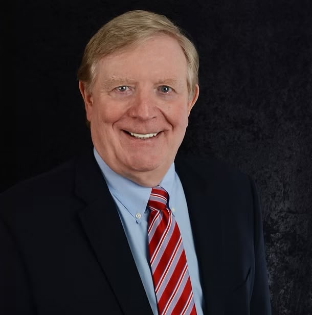 Professional headshot of man in suit and red tie